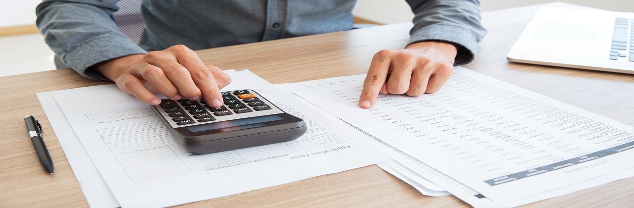 Close-up of unrecognizable man working with financial data. He using calculator and examining document. Financial inspector holding examination. Paperwork or finance concept